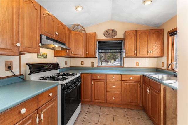 kitchen featuring gas range gas stove, sink, light tile patterned floors, and vaulted ceiling