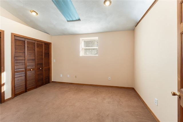 unfurnished bedroom featuring a closet, light colored carpet, and vaulted ceiling