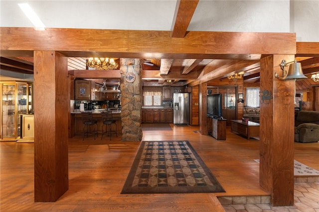 interior space with hardwood / wood-style floors, beam ceiling, wood walls, and bar area