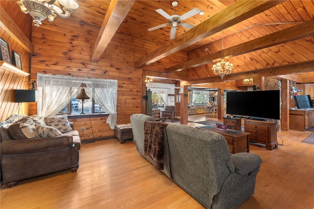 living room with lofted ceiling with beams, wooden walls, wood ceiling, ceiling fan with notable chandelier, and light wood-type flooring