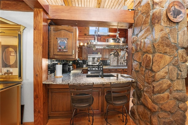 bar featuring sink, hardwood / wood-style flooring, light stone countertops, beam ceiling, and gas stove