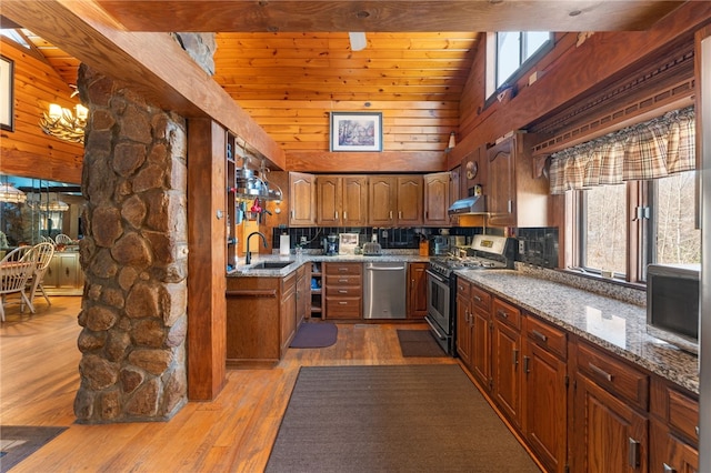 kitchen featuring sink, light hardwood / wood-style flooring, vaulted ceiling, stone countertops, and stainless steel appliances