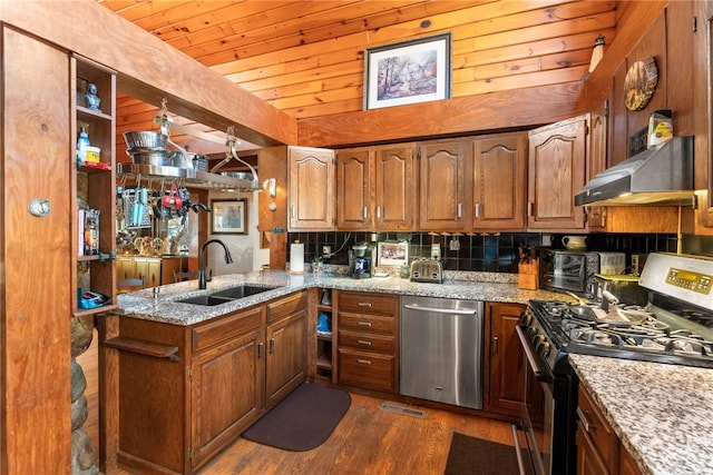 kitchen featuring light stone countertops, appliances with stainless steel finishes, dark hardwood / wood-style flooring, kitchen peninsula, and extractor fan