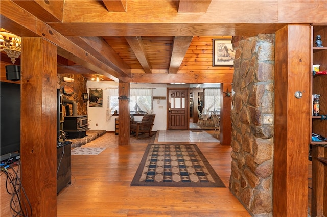 foyer with hardwood / wood-style floors, wood walls, a wood stove, beam ceiling, and wood ceiling