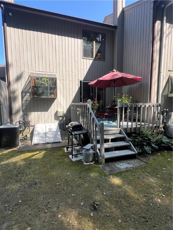 back of property with a lawn, central air condition unit, and a wooden deck