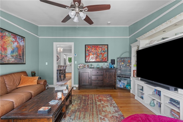 living room featuring crown molding, hardwood / wood-style floors, and ceiling fan with notable chandelier