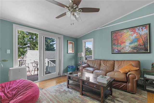 living room with a healthy amount of sunlight, crown molding, wood-type flooring, and vaulted ceiling