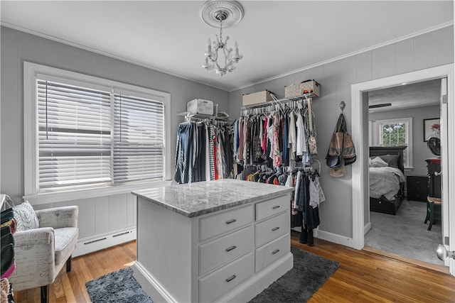 spacious closet featuring a notable chandelier, wood-type flooring, and baseboard heating