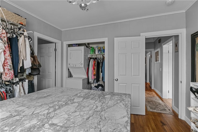 bedroom featuring ornamental molding, dark wood-type flooring, a closet, and stacked washer and clothes dryer