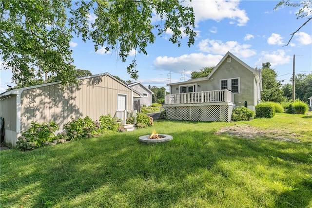 rear view of house featuring a lawn, a fire pit, and a wooden deck