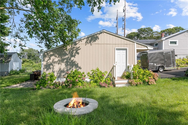 view of outbuilding with a yard and an outdoor fire pit