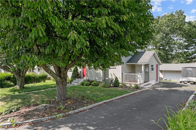 view of property hidden behind natural elements with a porch, a garage, and a front lawn