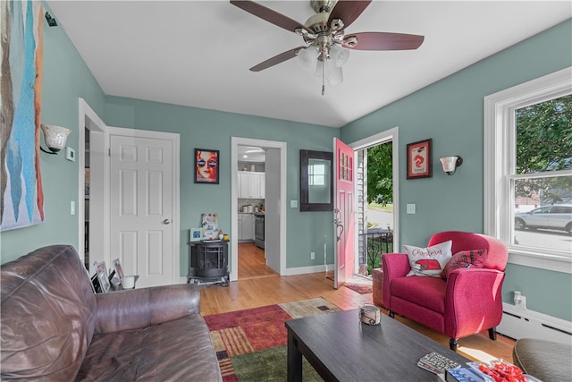 living room with light hardwood / wood-style flooring, ceiling fan, and a baseboard heating unit