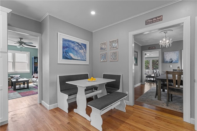 dining room with ceiling fan with notable chandelier, light hardwood / wood-style flooring, plenty of natural light, and ornamental molding