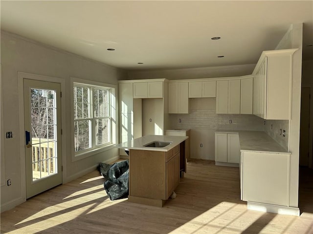 kitchen featuring white cabinets, decorative backsplash, a center island, and light hardwood / wood-style floors