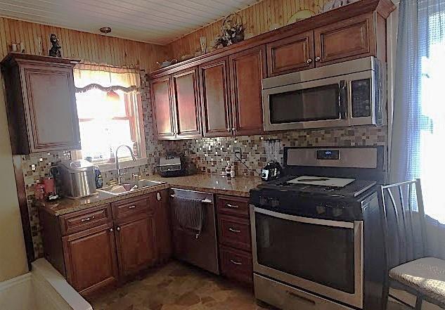 kitchen with tasteful backsplash, sink, wood walls, and appliances with stainless steel finishes