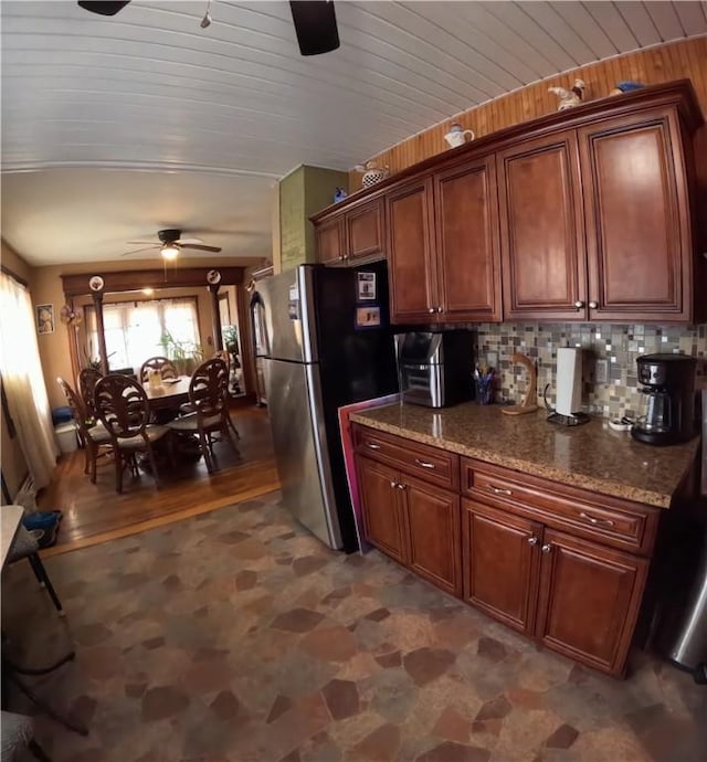 kitchen featuring wooden ceiling, stainless steel fridge, stone counters, ceiling fan, and decorative backsplash