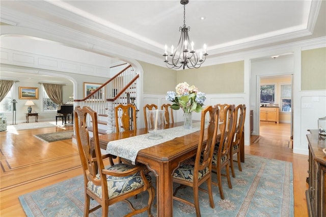 dining area featuring an inviting chandelier, crown molding, light hardwood / wood-style flooring, and a raised ceiling