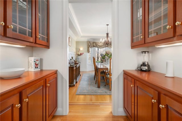 bar featuring crown molding, a notable chandelier, light hardwood / wood-style floors, and decorative light fixtures