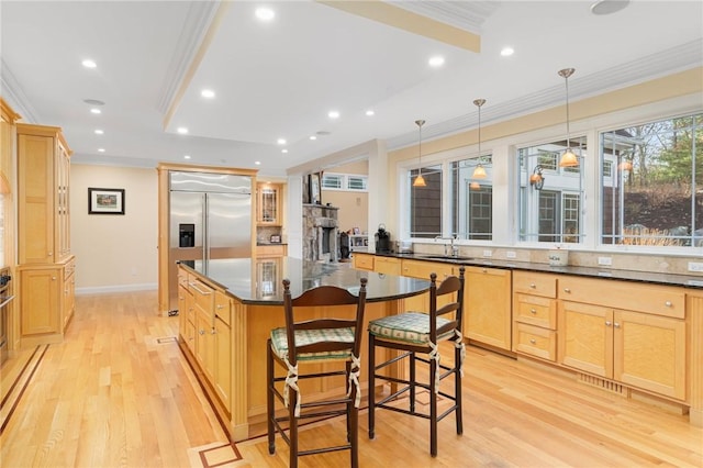 kitchen featuring pendant lighting, a kitchen breakfast bar, stainless steel built in refrigerator, ornamental molding, and a kitchen island