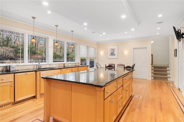 kitchen with pendant lighting, sink, ornamental molding, a kitchen island, and dark stone counters