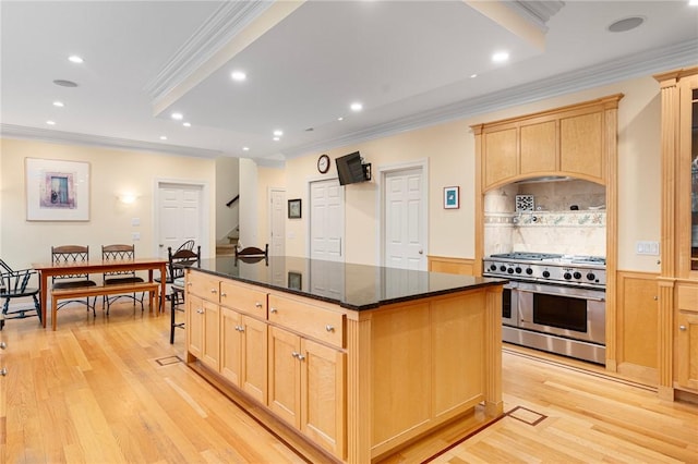 kitchen featuring light wood-type flooring, light brown cabinets, a center island, and range with two ovens