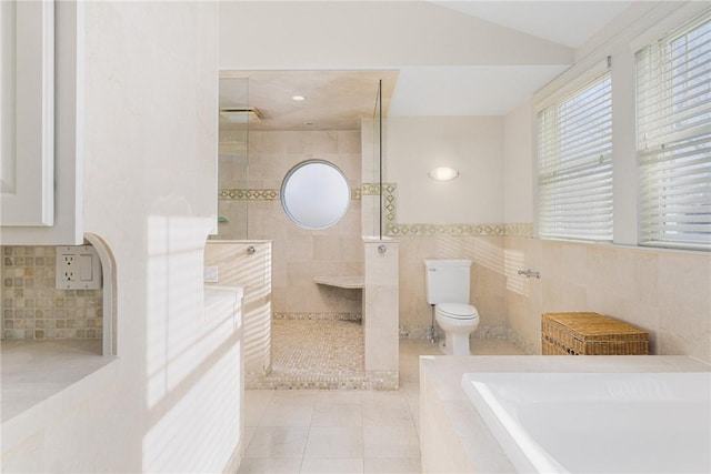 bathroom featuring tile patterned floors, toilet, vaulted ceiling, tile walls, and independent shower and bath