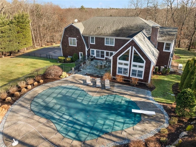 back of property with a yard, a covered pool, and a patio