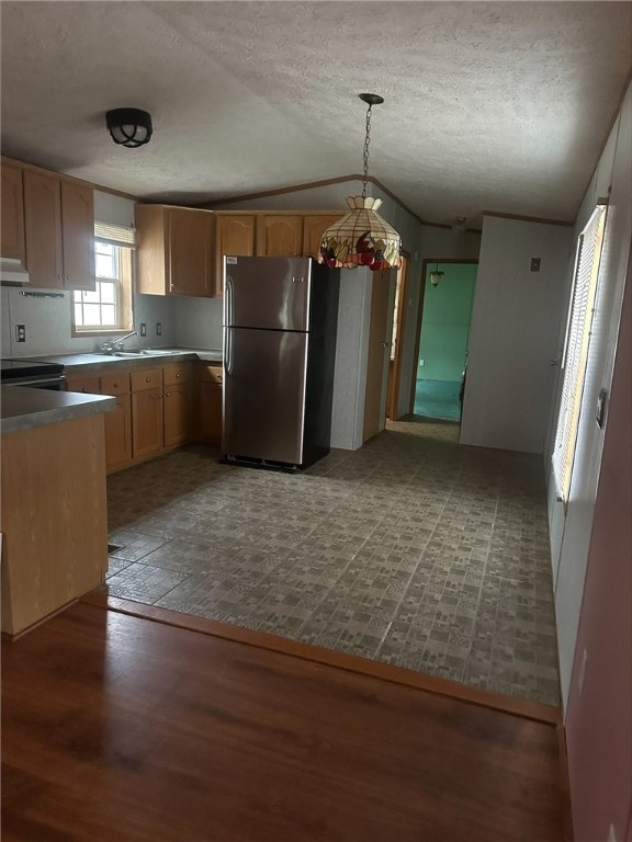 kitchen with stainless steel fridge, a textured ceiling, decorative light fixtures, and light brown cabinetry