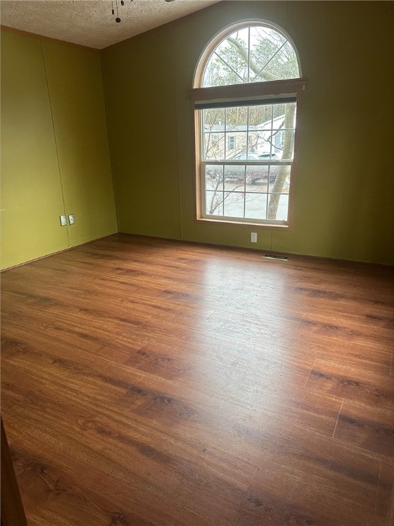 unfurnished room featuring ceiling fan, dark hardwood / wood-style flooring, and a textured ceiling