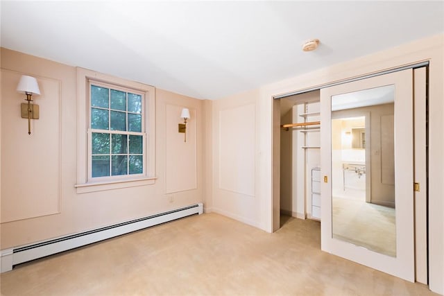 unfurnished bedroom with a closet, baseboard heating, and light colored carpet