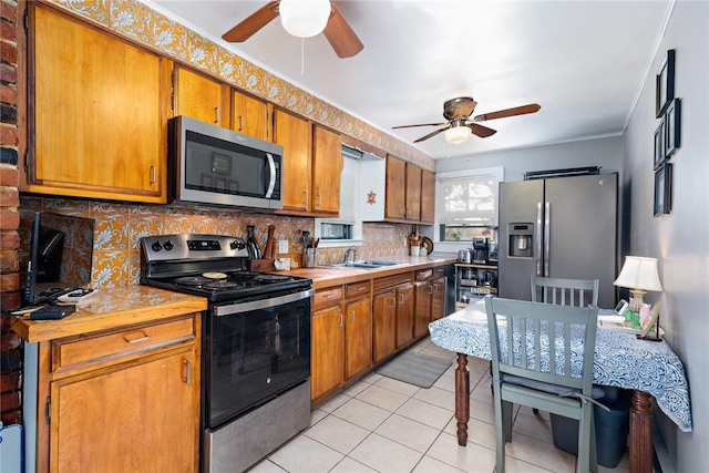 kitchen featuring backsplash, ceiling fan, sink, and stainless steel appliances