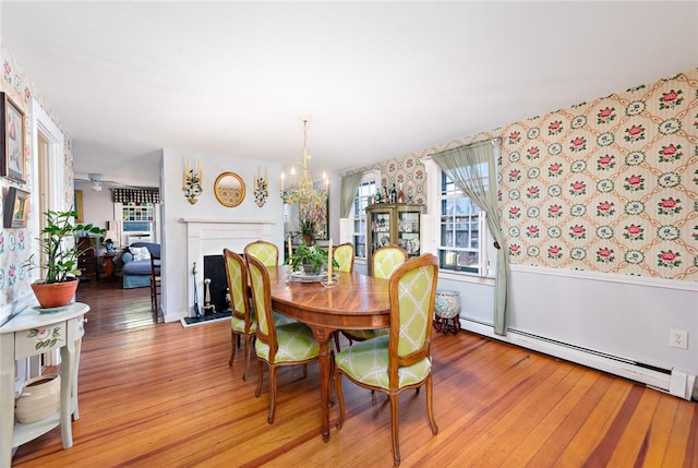 dining room with an inviting chandelier, light wood-type flooring, and a baseboard heating unit