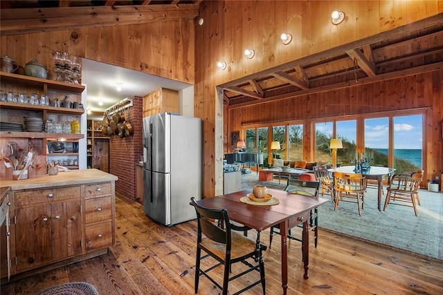 1635 Isabella Beach Rd, Southold, NY 06390 - kitchen with freestanding refrigerator, wooden walls, hardwood / wood-style floors, light countertops, and beam ceiling