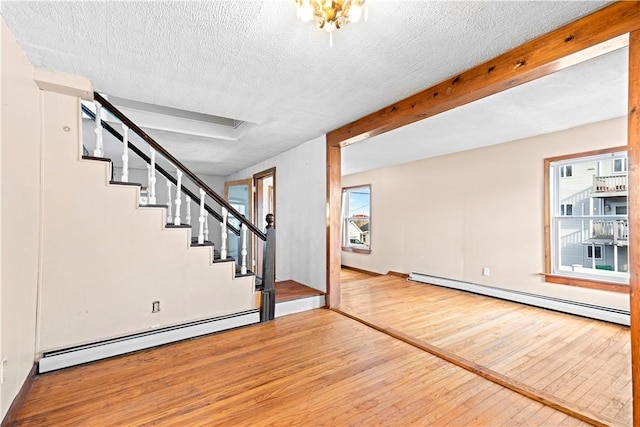 basement featuring wood-type flooring, a textured ceiling, and a baseboard heating unit