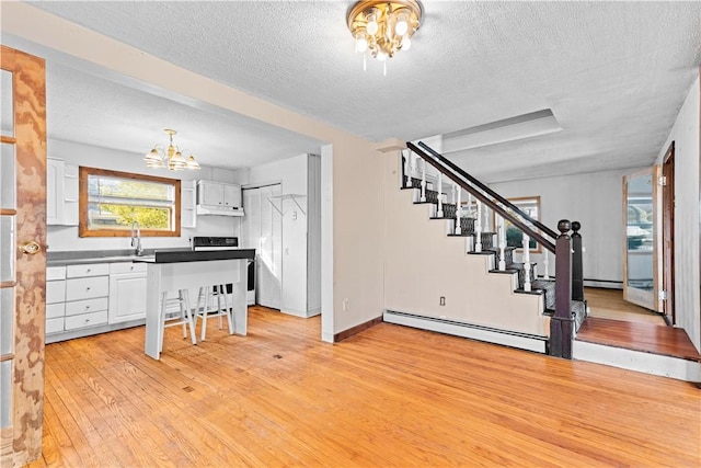 kitchen with white cabinets, light wood-type flooring, a notable chandelier, and a baseboard heating unit