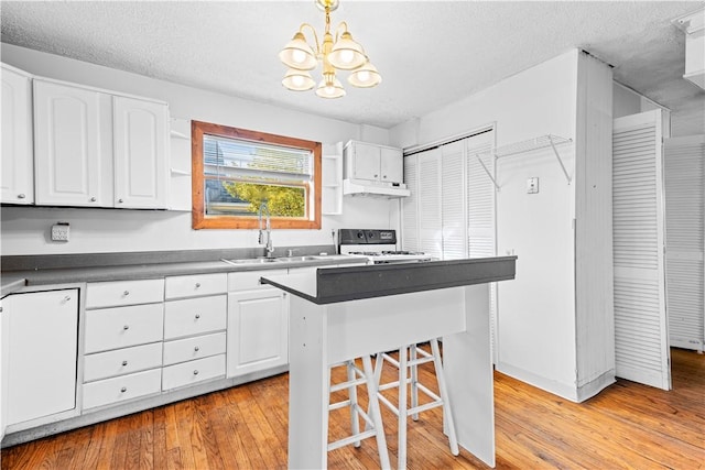 kitchen featuring white range oven, sink, white cabinets, and pendant lighting