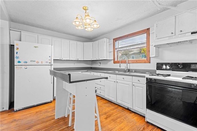 kitchen with white cabinets, a kitchen breakfast bar, white appliances, and sink