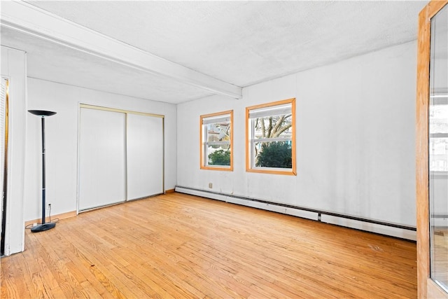 unfurnished bedroom featuring beamed ceiling, a textured ceiling, light hardwood / wood-style floors, and baseboard heating