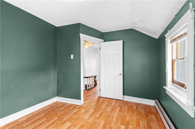 unfurnished bedroom with a baseboard radiator, lofted ceiling, and light hardwood / wood-style floors