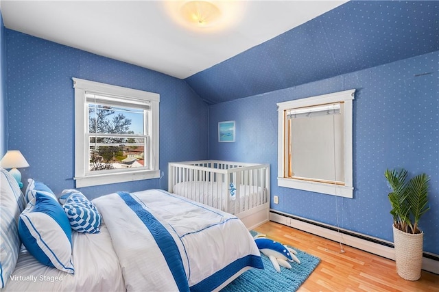 bedroom with hardwood / wood-style floors, vaulted ceiling, and baseboard heating