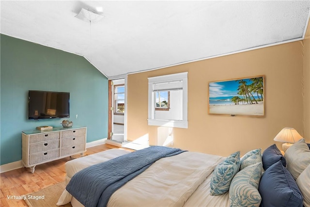 bedroom with light hardwood / wood-style floors and lofted ceiling