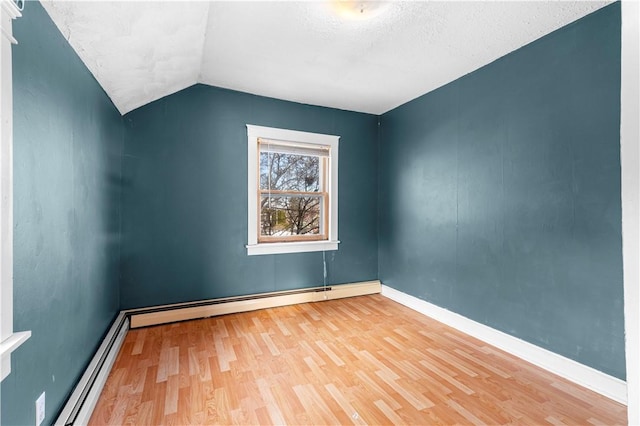 spare room with baseboard heating, light hardwood / wood-style flooring, a textured ceiling, and lofted ceiling