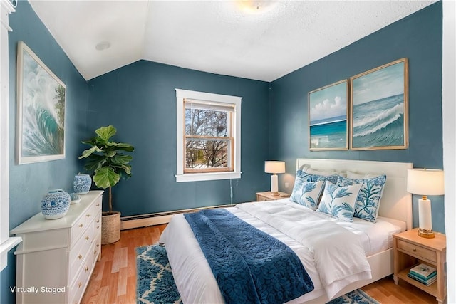 bedroom with a baseboard heating unit, light hardwood / wood-style floors, a textured ceiling, and vaulted ceiling