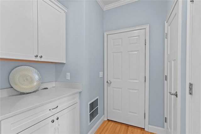 interior space featuring white cabinetry, light wood-type flooring, and ornamental molding