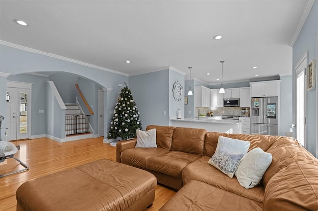 living room featuring light hardwood / wood-style flooring, crown molding, and ornate columns