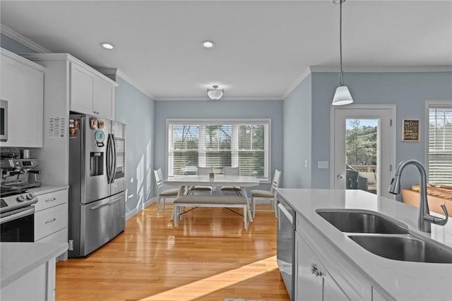 kitchen featuring white cabinetry, sink, stainless steel appliances, pendant lighting, and ornamental molding