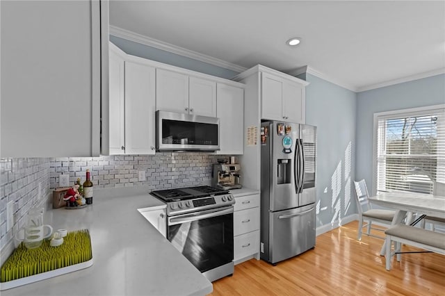 kitchen featuring decorative backsplash, appliances with stainless steel finishes, light wood-type flooring, ornamental molding, and white cabinetry