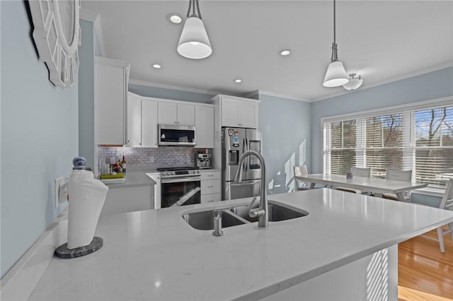 kitchen featuring white cabinets, sink, stainless steel appliances, and hanging light fixtures