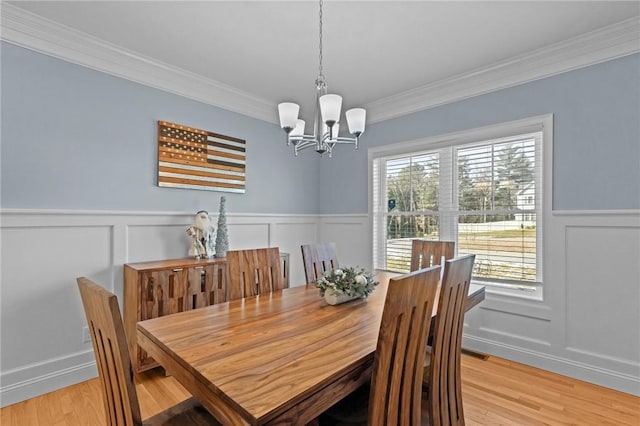 dining area with ornamental molding, light wood-type flooring, and a notable chandelier